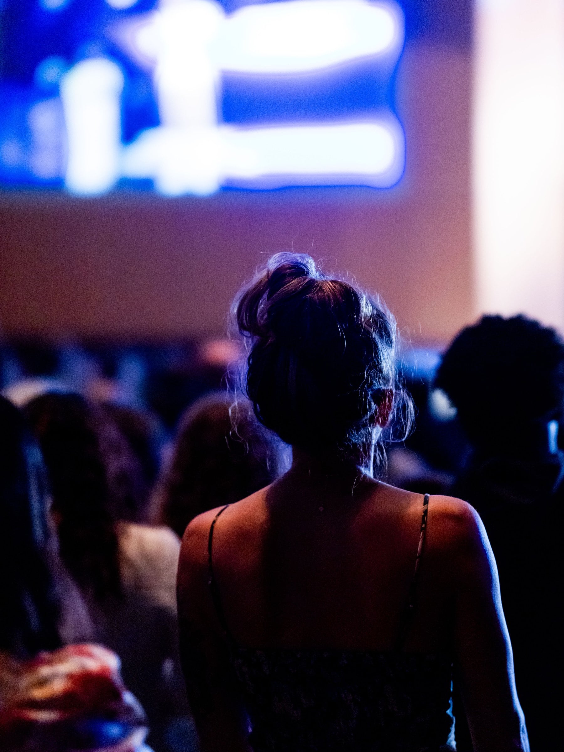 An audience in front of a blue screen, seen from behind